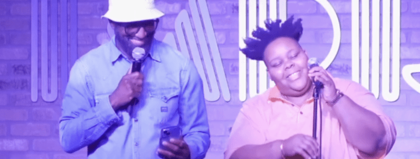 Two people performing on stage with microphones.